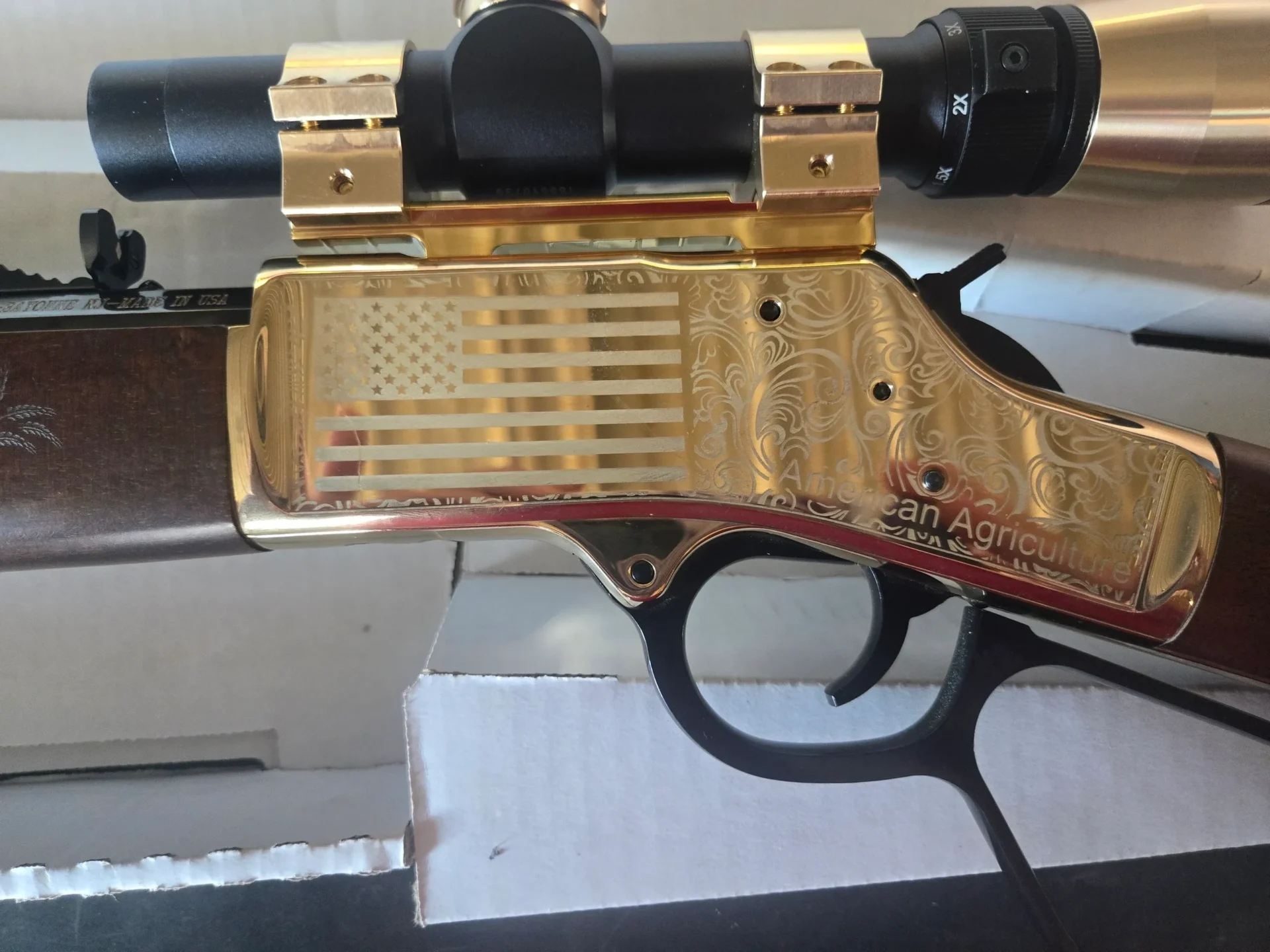 Gold-engraved rifle with mounted scope.