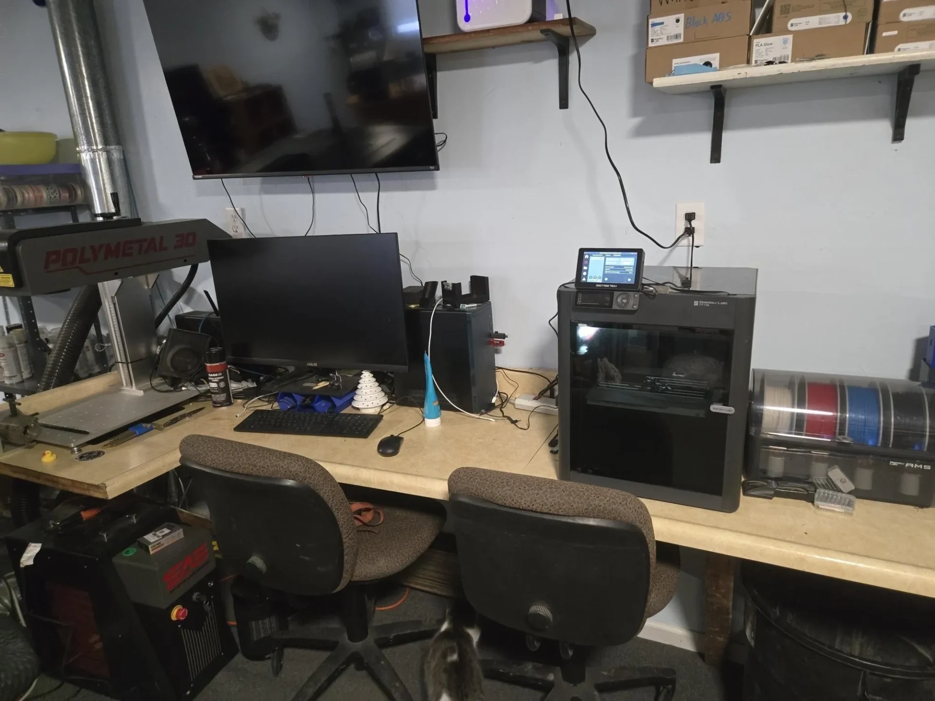 3D printing workshop with computer and equipment.